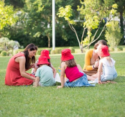 A family enjoys a summer picnic outdoors, bonding and relaxing in a sunny park setting.