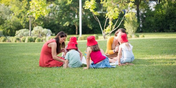 A family enjoys a summer picnic outdoors, bonding and relaxing in a sunny park setting.