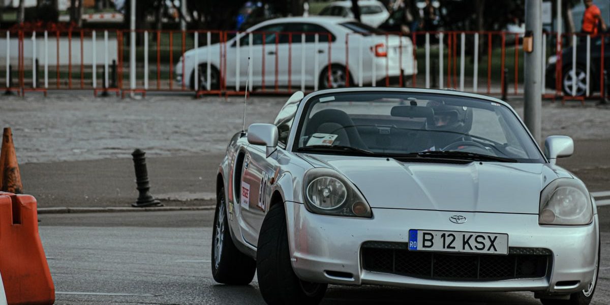 Silver cabriolet car racing in urban rally and driving on asphalt roadway in city