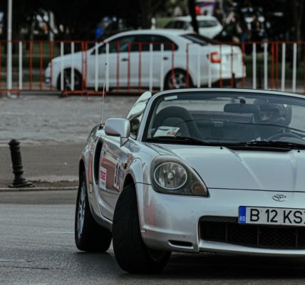 Silver cabriolet car racing in urban rally and driving on asphalt roadway in city