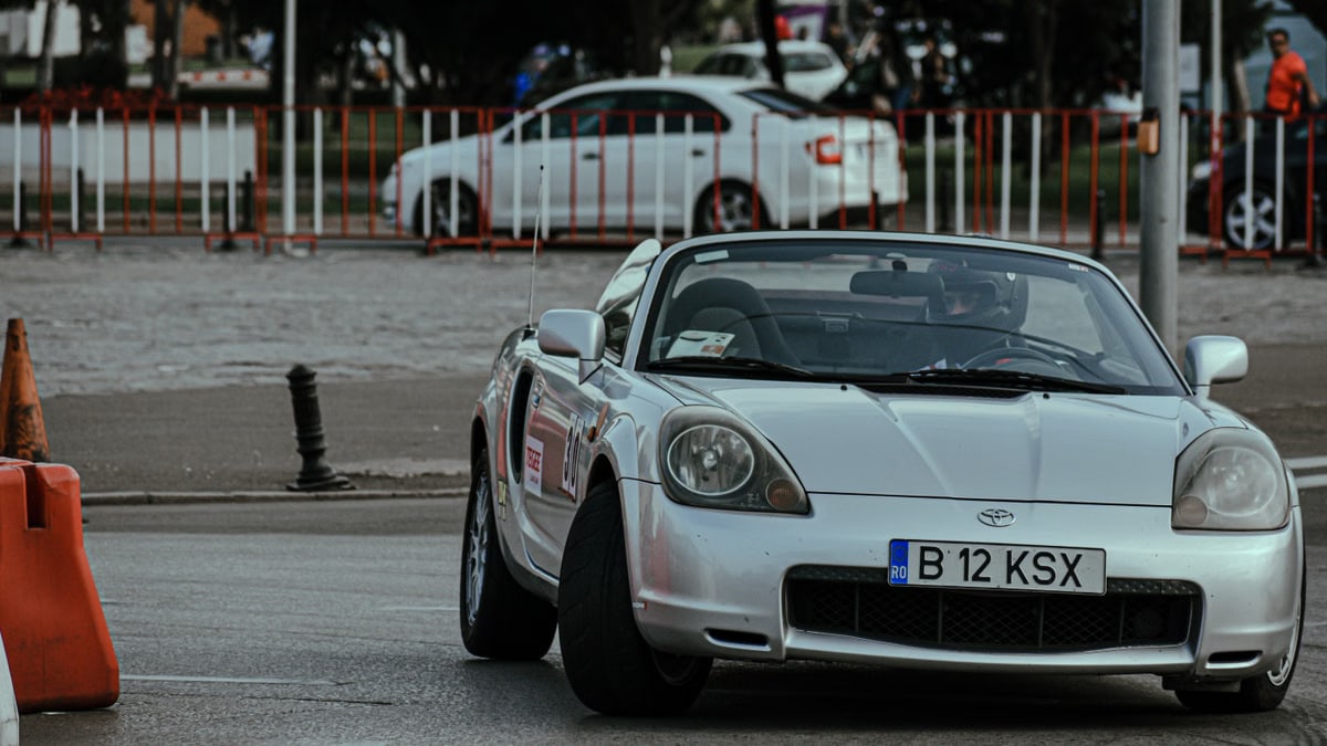 Silver cabriolet car racing in urban rally and driving on asphalt roadway in city